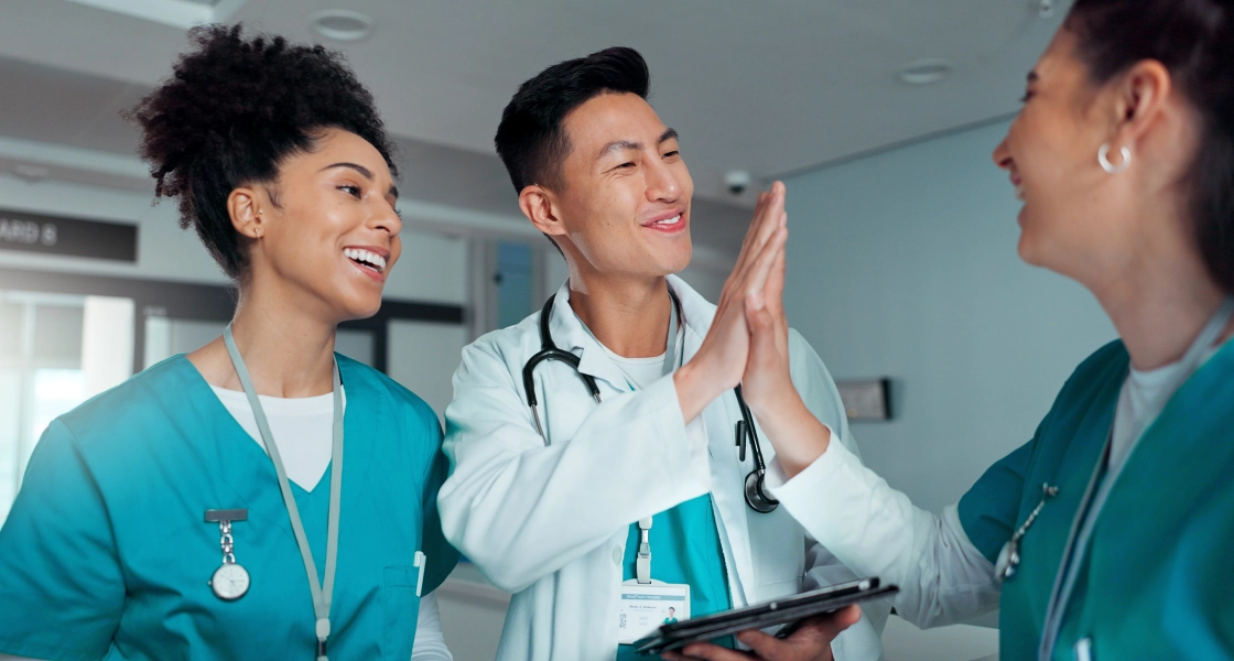 A male and Female travel nurse high five while another smiles next to them