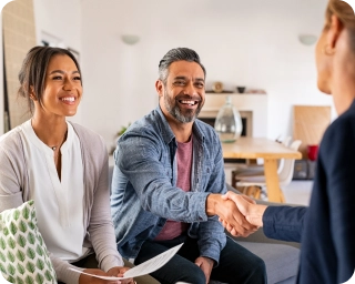 Two people across from another individual in the foreground shaking hands