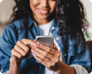 Woman in jean jacket looking at phone in foreground tapping the screen