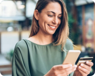 Woman in green shirt holding a phone with a credit card in her other hand