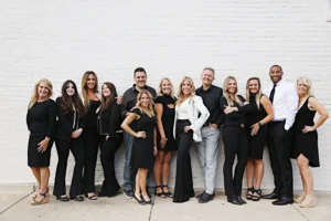 group of people standing in front of a white brick wall