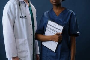a doctor and nurse standing next to each other, the nurse is holding a chart