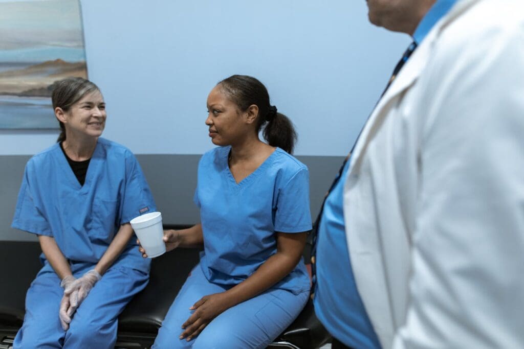 nurses talking to each other on a couch holding coffee